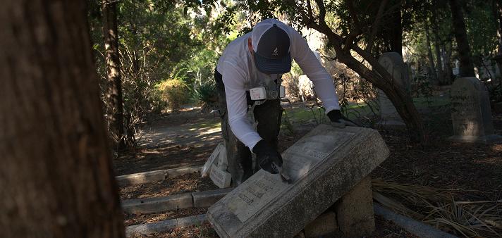 A fully insured Tending specialist carefully cleaning a gravestone, demonstrating our commitment to property protection and professional standards