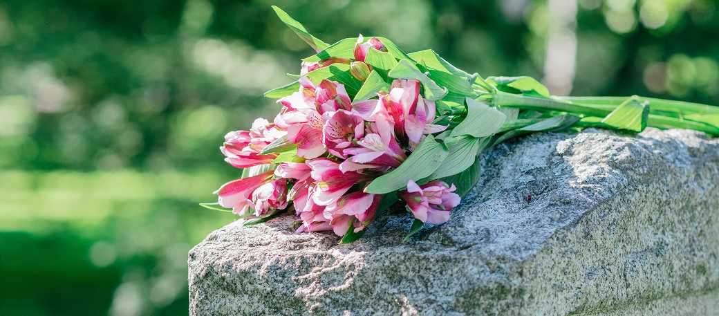 A well-kept grave with beautiful fresh flowers on the headstone, illustrating the peace of mind and consistency provided by professional remote grave care services.