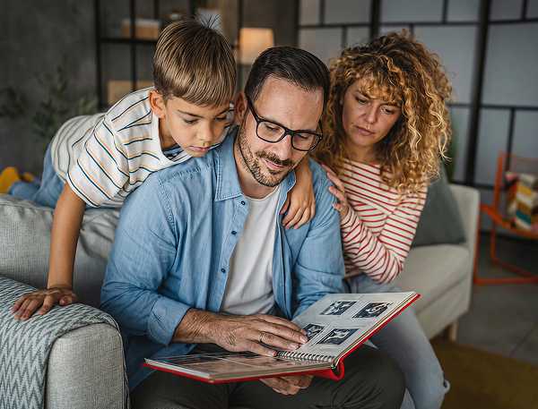 A family looking through an old photo album to remember their mother and grandmother