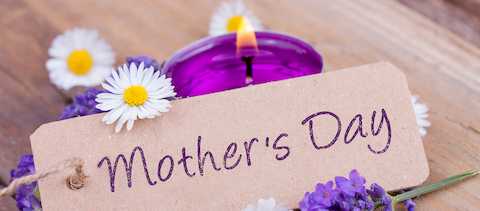 A candle and flowers honoring a deceased mother's memory on Mother's Day