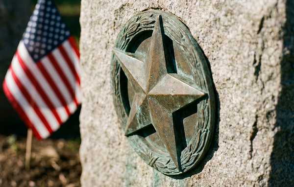A bronze memorial star plaque mounted on a stone headstone base