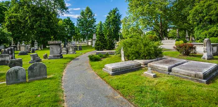 A scenic cemetery path lined with various granite and marble headstones