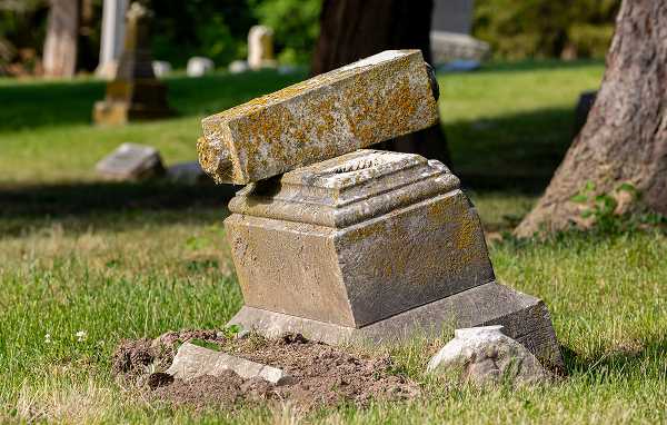 A severely damaged and eroded tombstone affected by acid rain and urban pollution