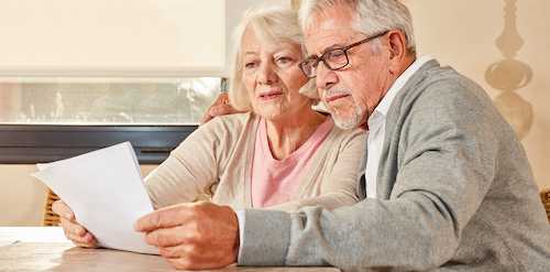 A senior couple reading plot paperwork and cemetery rules before planning a grave restoration