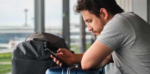 Man using a smartphone app to order remote grave care and headstone cleaning services from afar