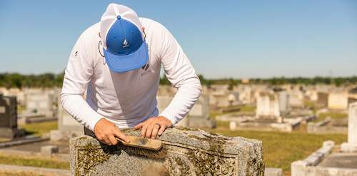 Tending specialist providing professional headstone cleaning services at a cemetery