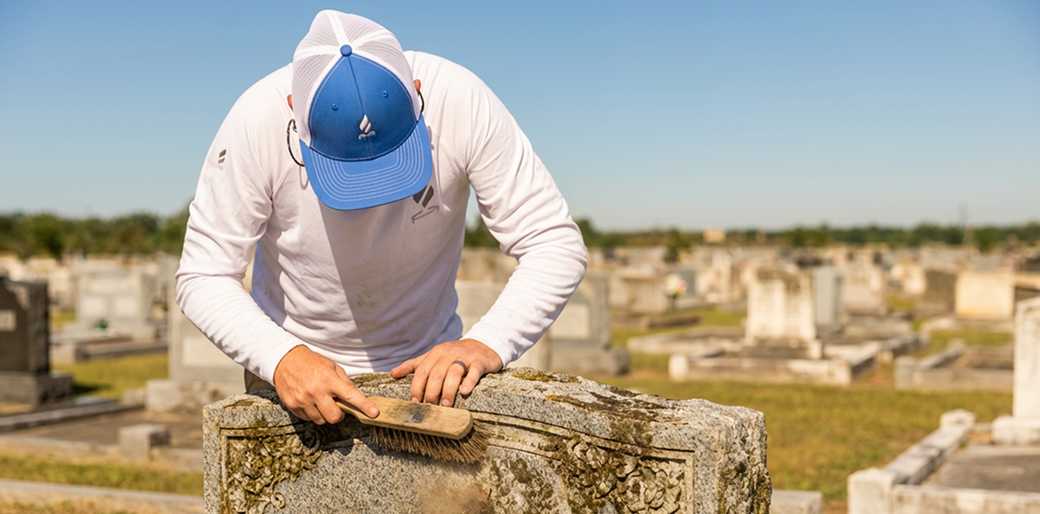 Tending specialist providing professional headstone cleaning services at a cemetery