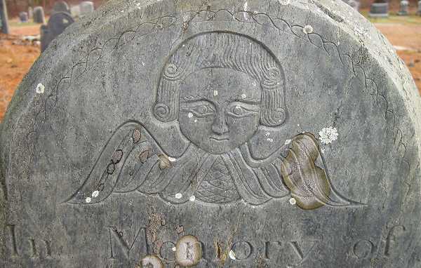 An early colonial New England gravestone featuring a winged death's head carving