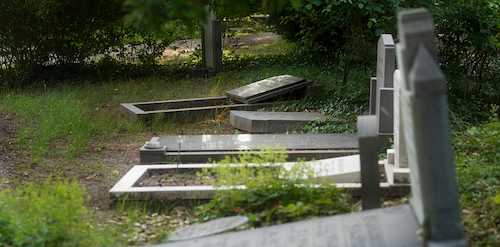 A fallen and leaning cemetery headstone needing professional foundation repair and resetting