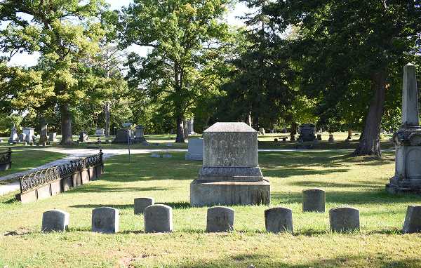 A large family monument surrounded by smaller gravestones in a cemetery plot