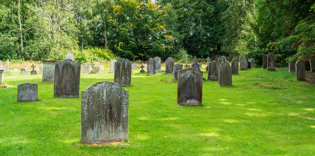 Weathered old tombstones in a historic cemetery showing delicate surfaces that can be permanently damaged by pressure washing.