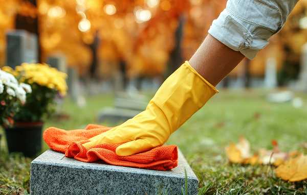 A Tending employee carefully wipes the tombstone.
