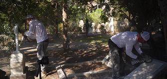 Two professionals from Tending are restoring gravestones at a cemetery